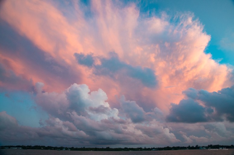 Orange, sunlit cumulunimbis cloud in back, pinkish stratocumulus below.